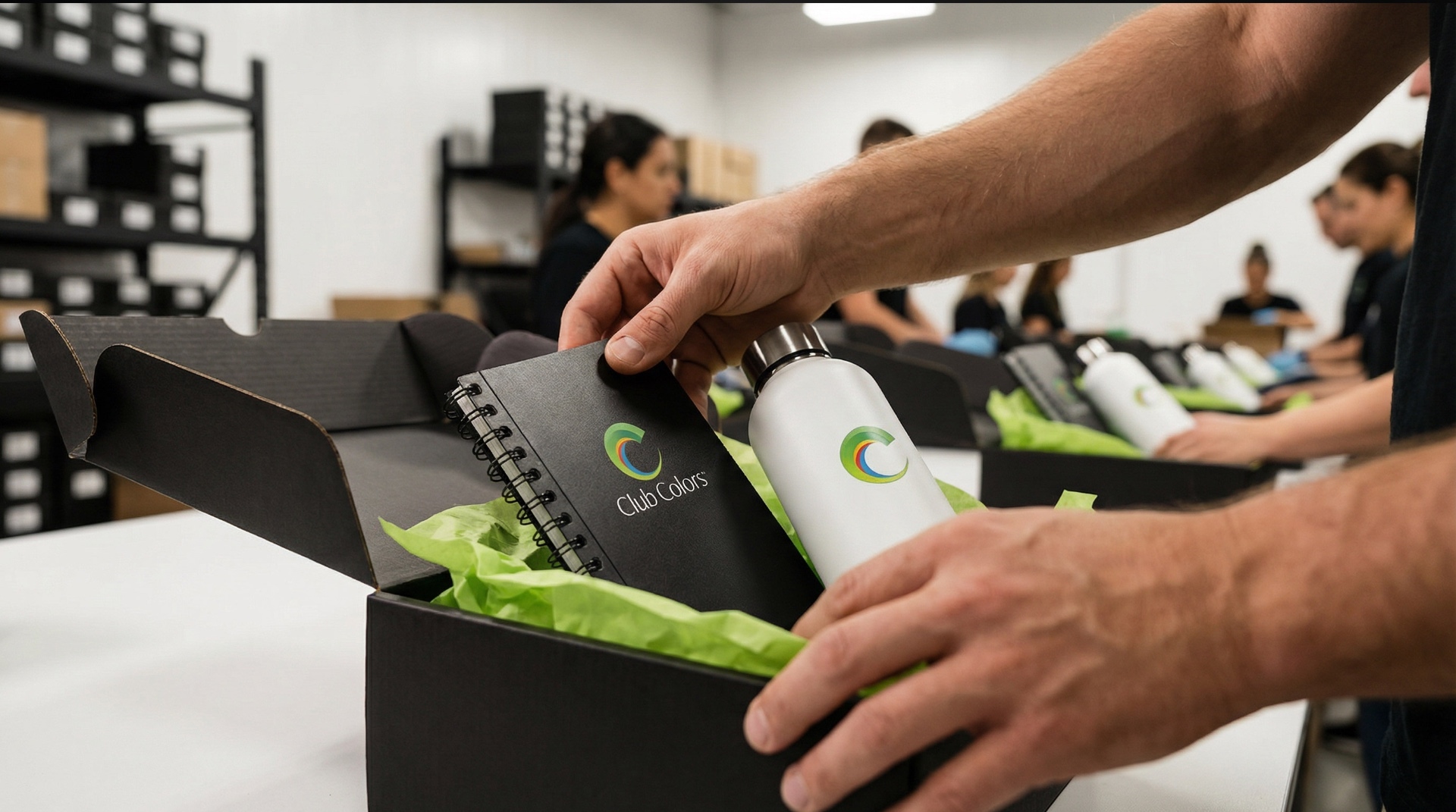 A Club Colors team member packing branded drinkware into a kitted gift box